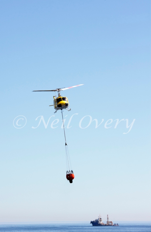 One of Cape Town's 'Working on Fire' Emergency Aerial Fire Fighting Helicopters collects water from the Atlantic Ocean off Sea Point, Cape Town, Western Cape, South Africa. 2015.